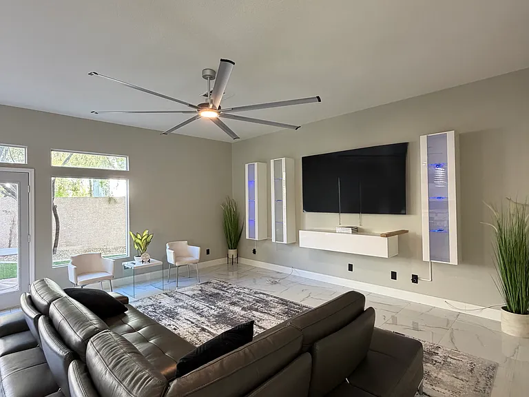 Furnished living room featuring designer seating, an oversized expandable sectional, swivel accent chairs, and a wall-mounted TV.