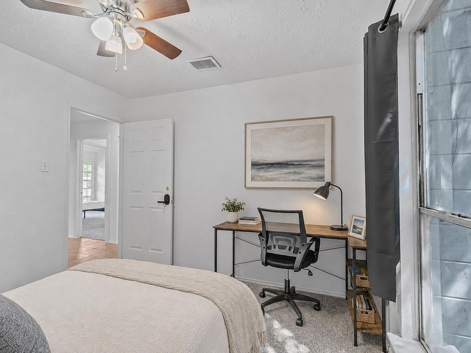 Bedroom with a full bed, dedicated desk setup, ceiling fan, and a large window for natural light.