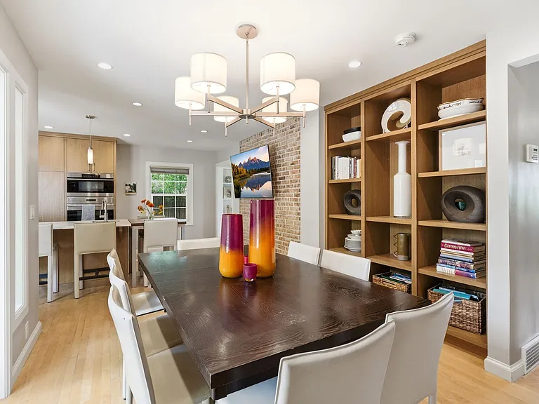Dining room with beautiful built in shelving, lots of windows and patio entrance as well as adjacent kitchen and bar nook.