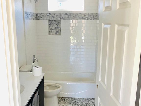 Main Bath with all new fixtures, spacious vanity, and a shower with subway tile, a recessed shelf, and accents matching the stone flooring.
