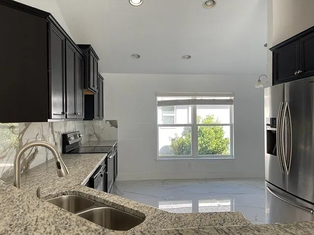 Modern kitchen with a sleek granite countertops, equipped with the convenience of a dishwasher, microwave, and refrigerator. stylish and functional space designed for your enjoyment. - 7019 Wirevine Dr