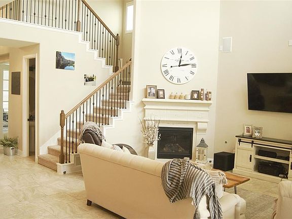 Looking back at entryway from the rear door. Beautiful stone fireplace and spindled staircase.