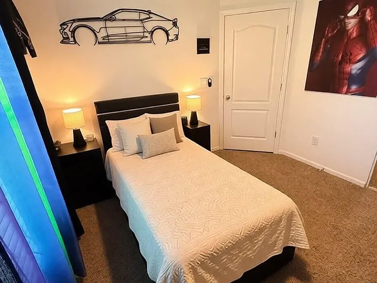 Private bedroom with a full-size bed, dual nightstands, ceiling fan, and carpeted flooring for comfortable everyday living.