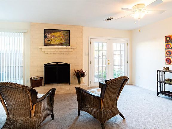 Enter from the car port and patio area to the spacious den with wood burning fireplace.