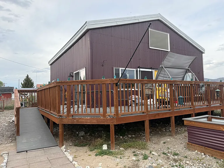 Side ramp to fenced front porch with porch swing and gas grill