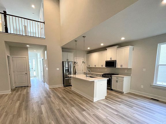 2-story family room open to the island kitchen with white cabinets, white counters and medium toned