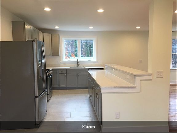 Tiled floor kitchen featuring travertine counter and bar, wood cabinetry (including Lazy-Susan pantry. Stainless refrigerator, dishwasher, and sink with push button garbage disposal. Windows open outward.