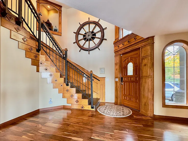 __ Elegant Entryway Anchored by an Original 8' Mosquito Fleet Ship's Wheel A striking nautical centerpiece_an authentic 8-foot ship's wheel from the historic Mosquito Fleet_sets the tone in this warm, wood-accented entryway.