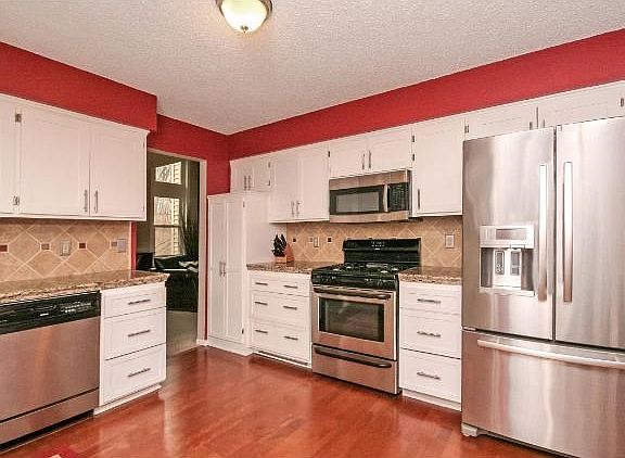 Open eat-in kitchen with stainless appliances and granite counters and patio door to decks