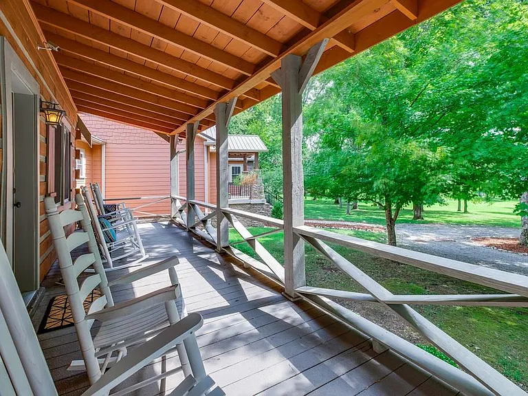 Front porch with four rocking chairs and a porch swing.