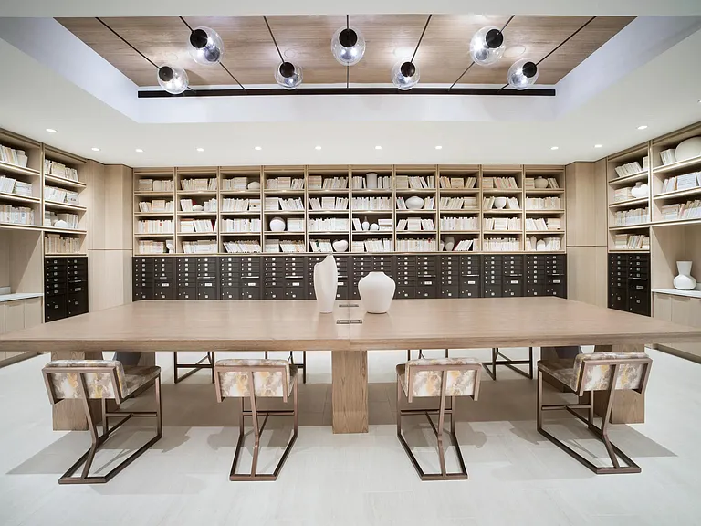 A dual-purpose mailroom and workspace featuring a communal table, custom shelving, and an organized setting for daily routines and focused tasks.