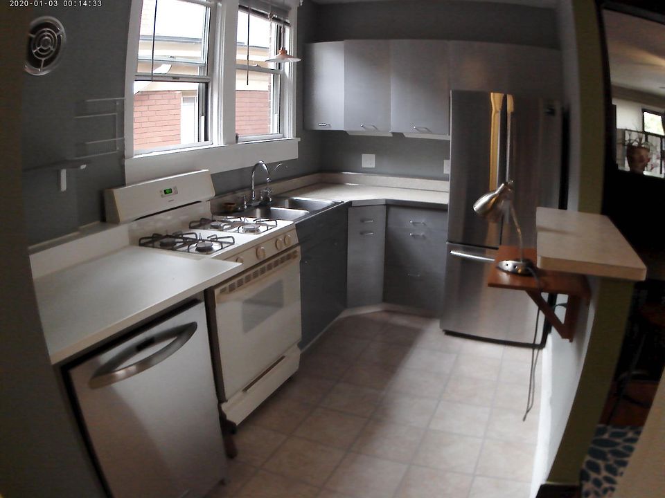 High end appliances adorn this kitchen. The upper right is a peel into the Living space with shelving for plants lining the antique windows.