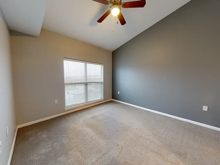 The Sycamore's bedroom includes a large window, ceiling fan, accent wall, and carpet. The Sycamore's bedroom includes a large window, ceiling fan, accent wall, and carpet.
