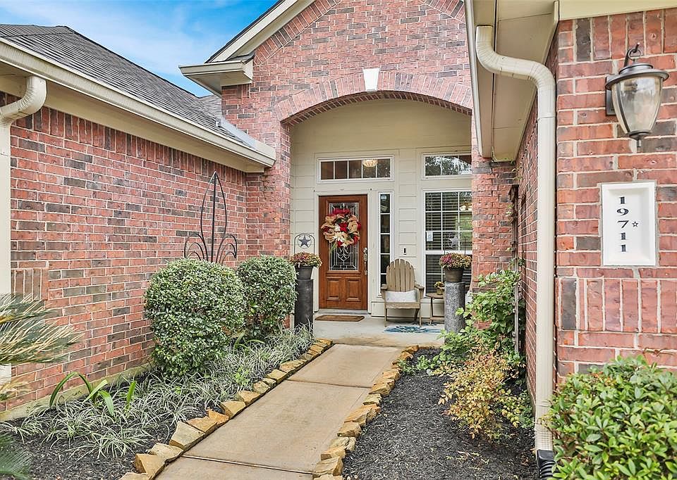 Welcoming sidewalk to arched covered porch with room for seating. Solid wood entry door with lead glass inset and sidelight. Mature plantings and colorful vines.