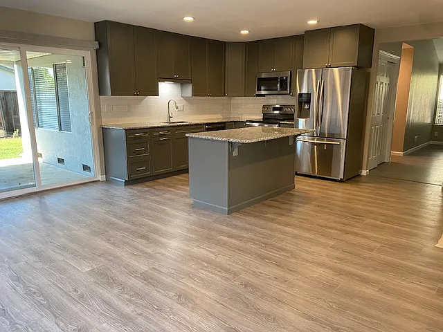 Remodeled kitchen with stainless steel appliances, granite countertops, tile backsplash and island.