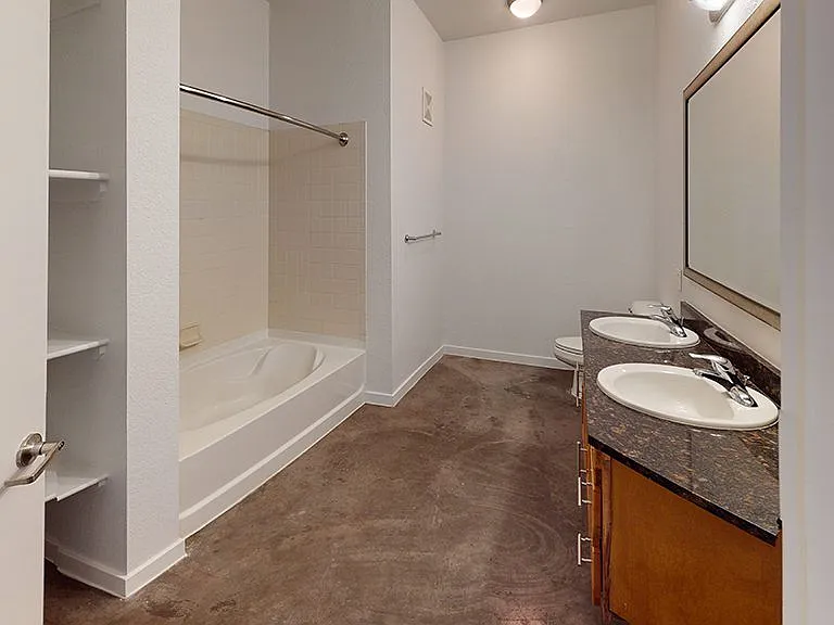 Apartment bathroom with polished concrete flooring and double sinks.