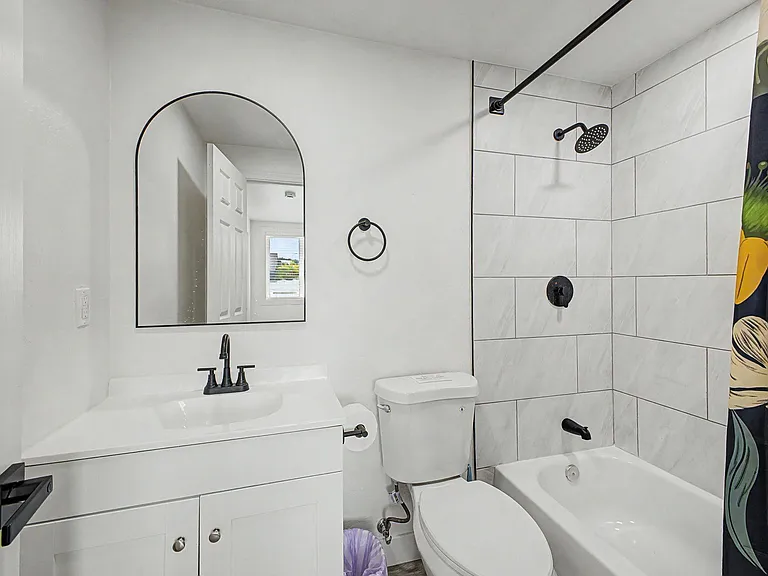 Updated bathroom with tiled tub/shower surround, single-sink vanity, and matte black fixtures for everyday convenience.