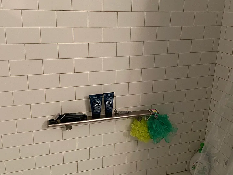 Grab bar and ceramic shower tile in shower.