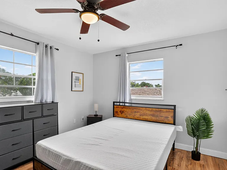 Well-sized bedroom with two windows, ceiling fan, and space for a full/queen bed plus dresser and nightstand.