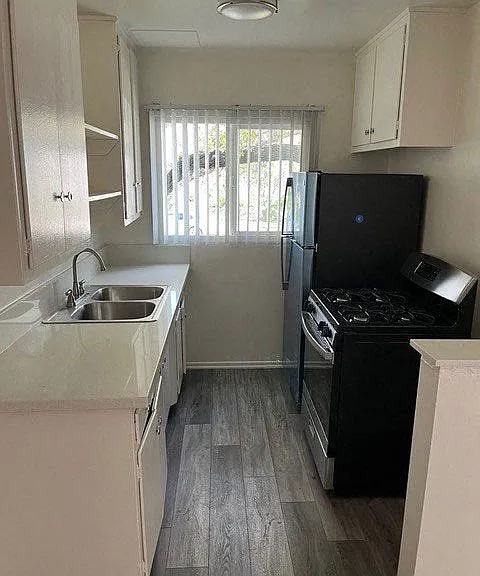 Kitchen with wood plank style flooring, white cabinets, and gas range at Los Robles Apartments in Pasadena, California.