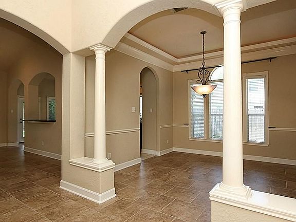 Elegant formal dining room has an arched double column entry, vaulted ceiling with double crown mold