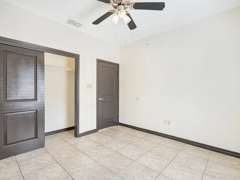 Unoccupied room in La Joya Apartments, Laredo, Texas, showcasing a ceiling fan and a tile floor