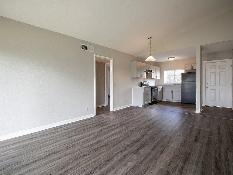 Bright open-plan apartment interior with sleek laminate flooring, modern kitchen appliances, and elegant lighting fixtures.