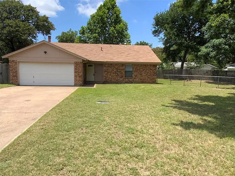 Brick exterior with a peaked roofline, attached two-car garage, concrete driveway, and front lawn