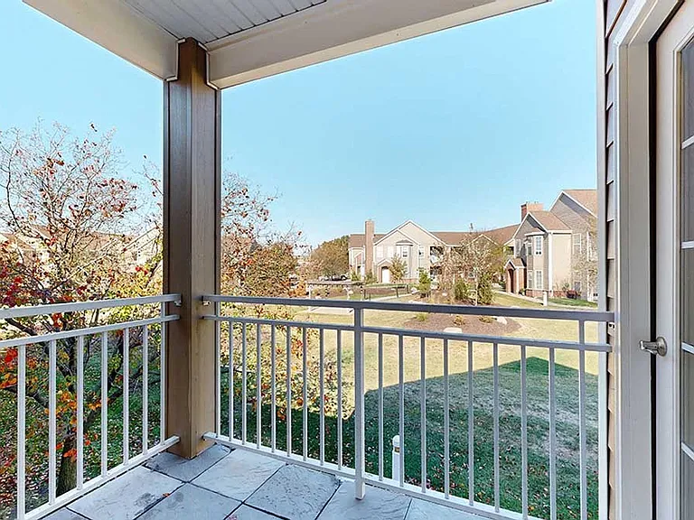 Enjoy serene views from your private balcony, overlooking a landscaped green space and nearby residential buildings.