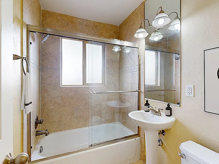 Elegant bathroom with modern fixtures, glass-enclosed tub, and artistic decor.