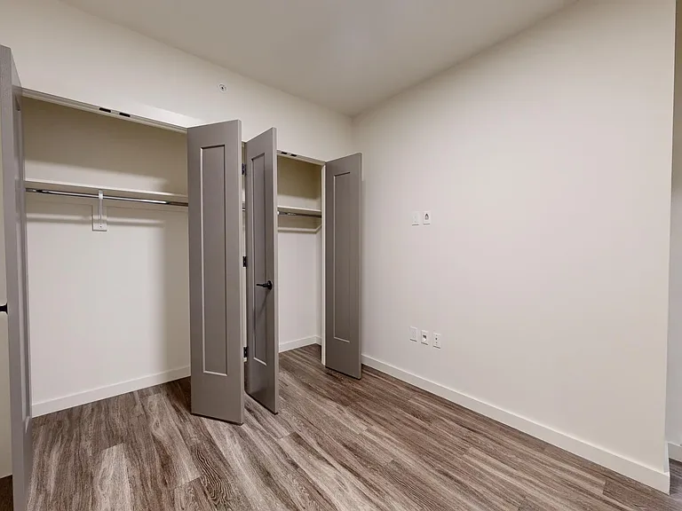 Spacious apartment bedroom with wood-style flooring.
