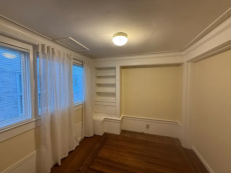 Downstairs bedroom with hardwood floors, west-facing windows, charming built-ins