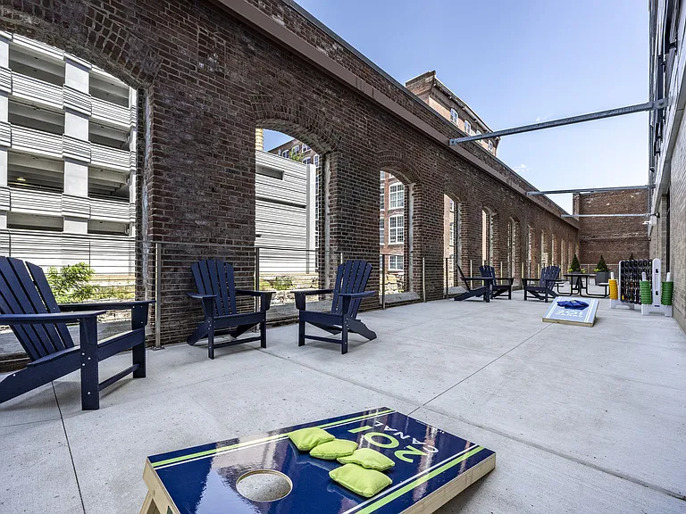 Canal-Side Courtyard With Adirondack Chairs And Cornhole