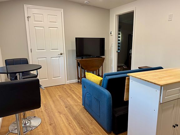 The kitchen island is on wheels in this open plan living room kitchen area. You can see the door the bathroom (closed) and the door to the 2nd bedroom.