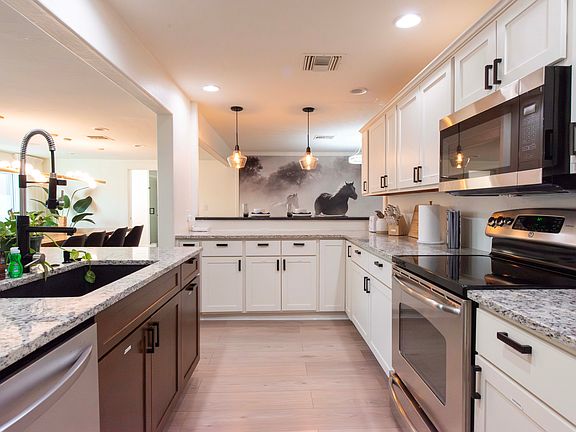 Expansive and fully equipped kitchen with dishwasher, oven/cooktop, microwave, wine chiller, refrigerator with ice maker and water dispenser, Kitchen Aid mixer, coffee maker, and bar area seating.