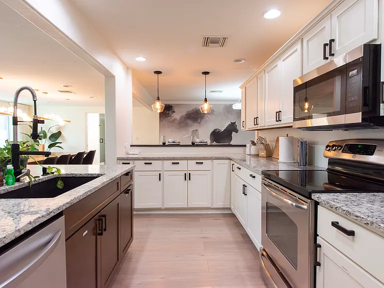 Expansive and fully equipped kitchen with dishwasher, oven/cooktop, microwave, wine chiller, refrigerator with ice maker and water dispenser, Kitchen Aid mixer, coffee maker, and bar area seating.