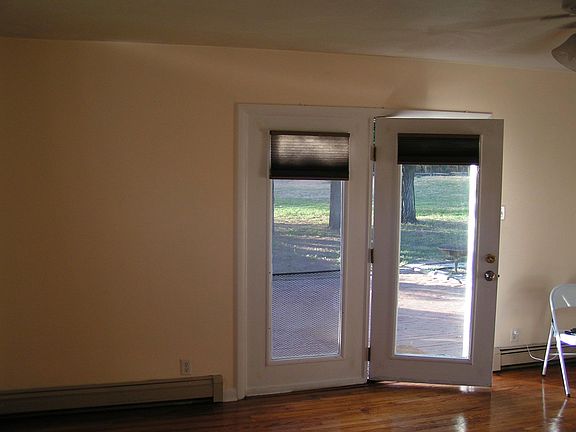 The living room has hardwood floors, and looks out at the brick terrace and large yard.