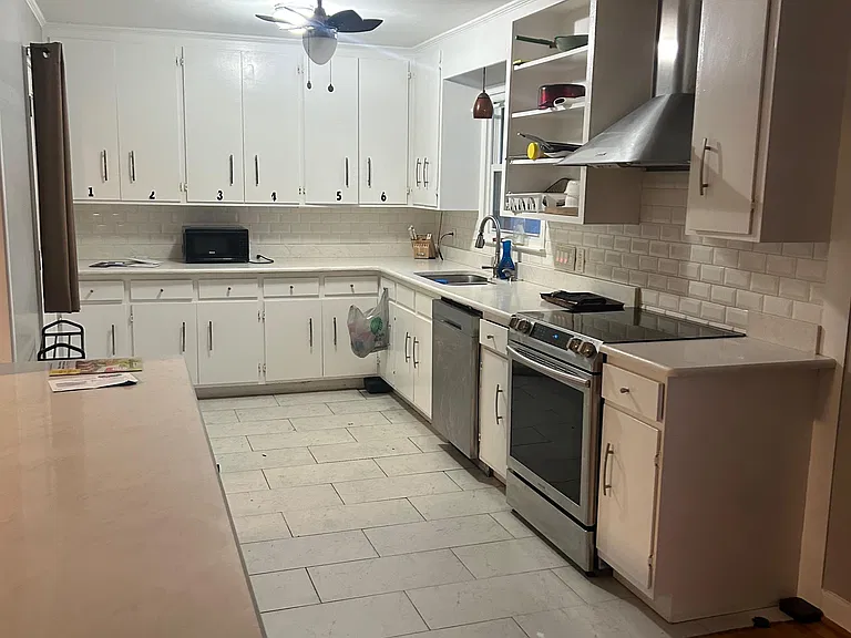 Spacious kitchen with extensive cabinet storage, long countertops, and stainless-steel range, hood, and dishwasher.