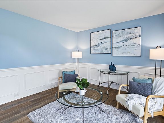 Sunny, bright living room with new flooring and crisp white wainscoting