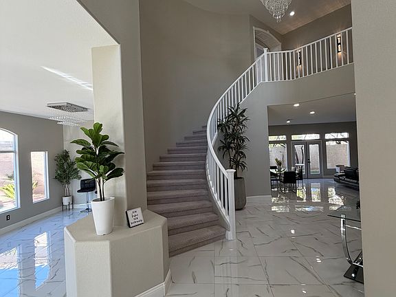 Elegant entry with soaring staircase, chandelier, and views into the open-concept living and dining spaces.