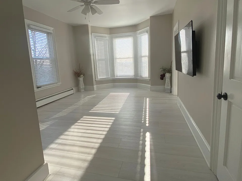 A bright, welcoming living space with brand-new flooring, natural light throughout the day, and a convenient secondary entry option.