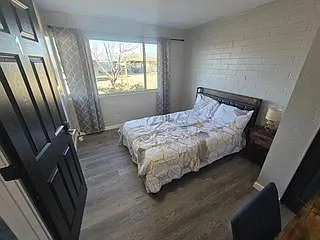 Bedroom offers a full bed, wide window with curtains, and durable flooring for easy upkeep and comfortable daily living.