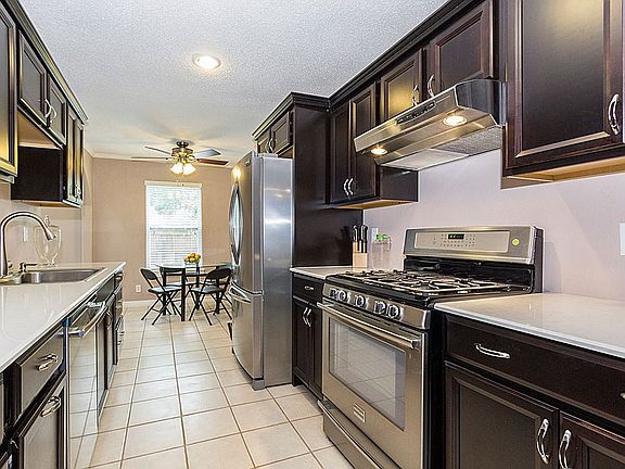 Stainless steel appliances include 5-burner gas range, oversized double basin sink with one-arm pull down faucet and dishwasher.