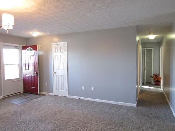 Hall way to bedrooms with same gray paint and brown/gray carpet.
