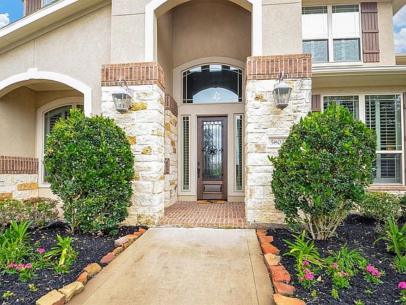 Walking up to the brick porch with wood and iron front door.