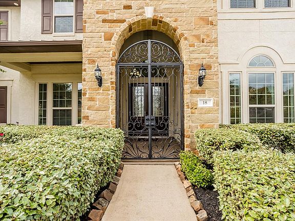Mature landscaping surrounds the walkway that leads to a handsomely gated archway and covered front porch.