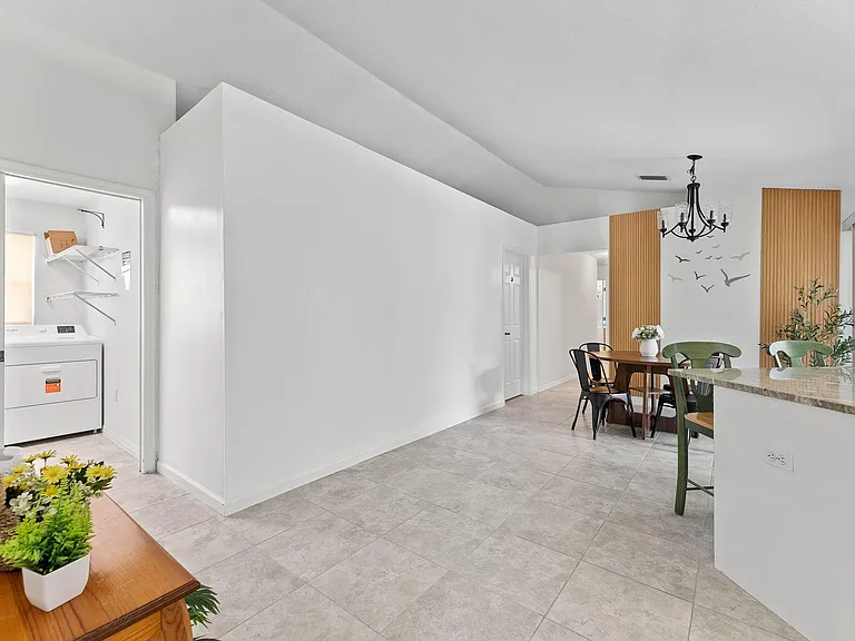 Open dining area with tile floors, chandelier lighting, and easy access to the kitchen counter and nearby laundry nook.