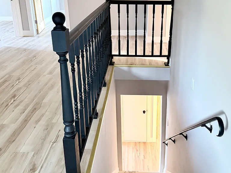 Elegant staircase with black railing leading to the second floor loft.