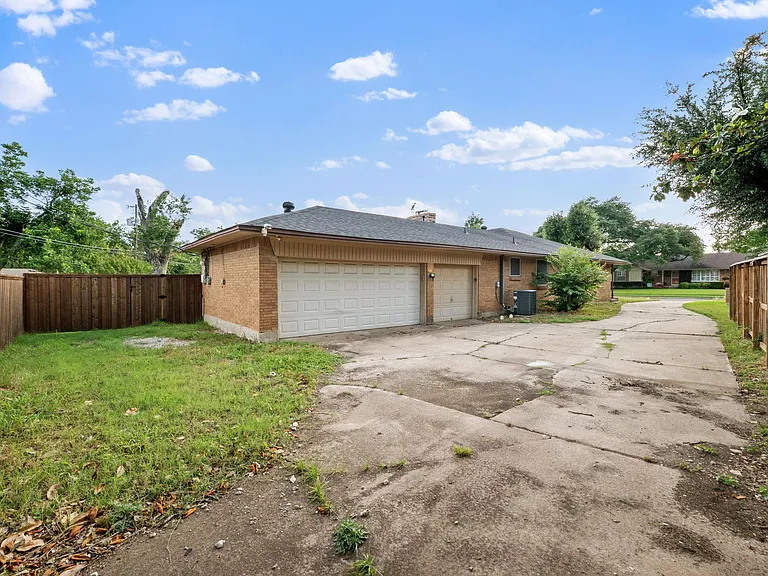 Long driveway leads to a two-car garage with side entry and fenced yard space for added privacy and storage.