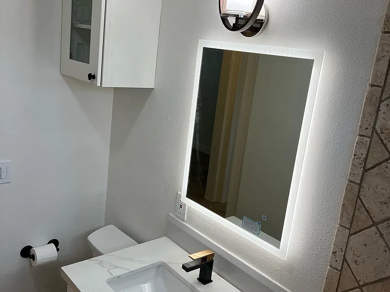 Bathroom photo with all new vanity, lighted mirror, new light, faucet, new toilet and new cabinet with light